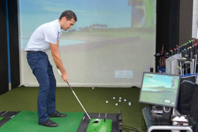 young golf player having fun playing on a golf simulator