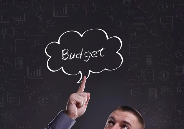 A man pointing to a chalk-drawn thought cloud that contains the word "Budget"